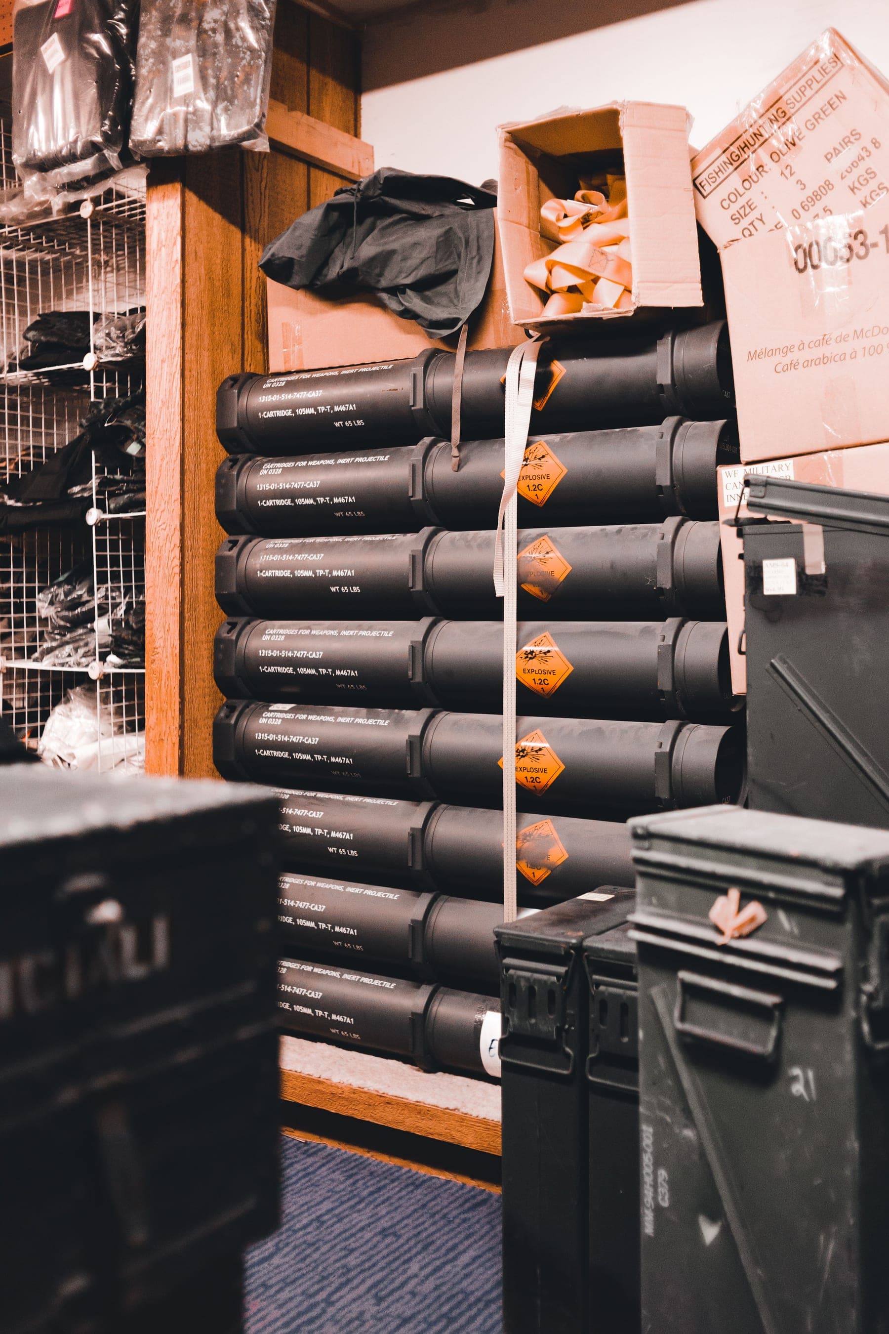 Stacked inert ordnance transport tubes marked with UN 0328 explosive classification labels and NSN part numbers