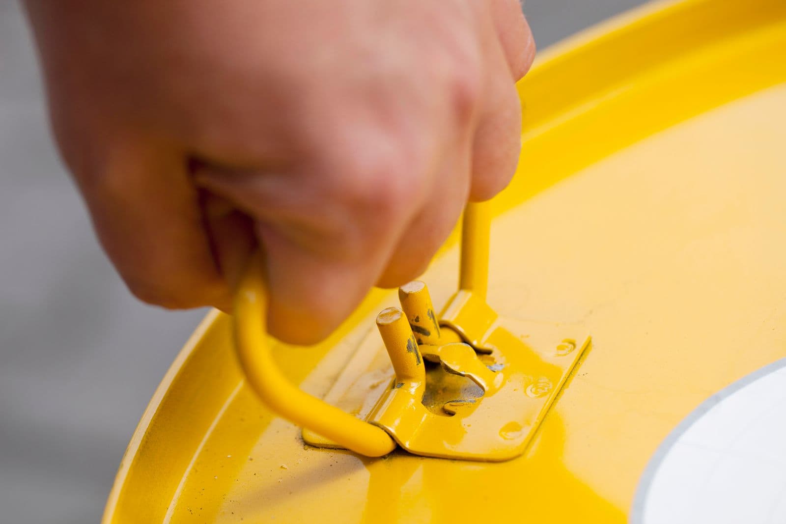 Close-up of a hand operating an industrial drum lever-lock closure, representative of the jerricans and drums tested on this page
