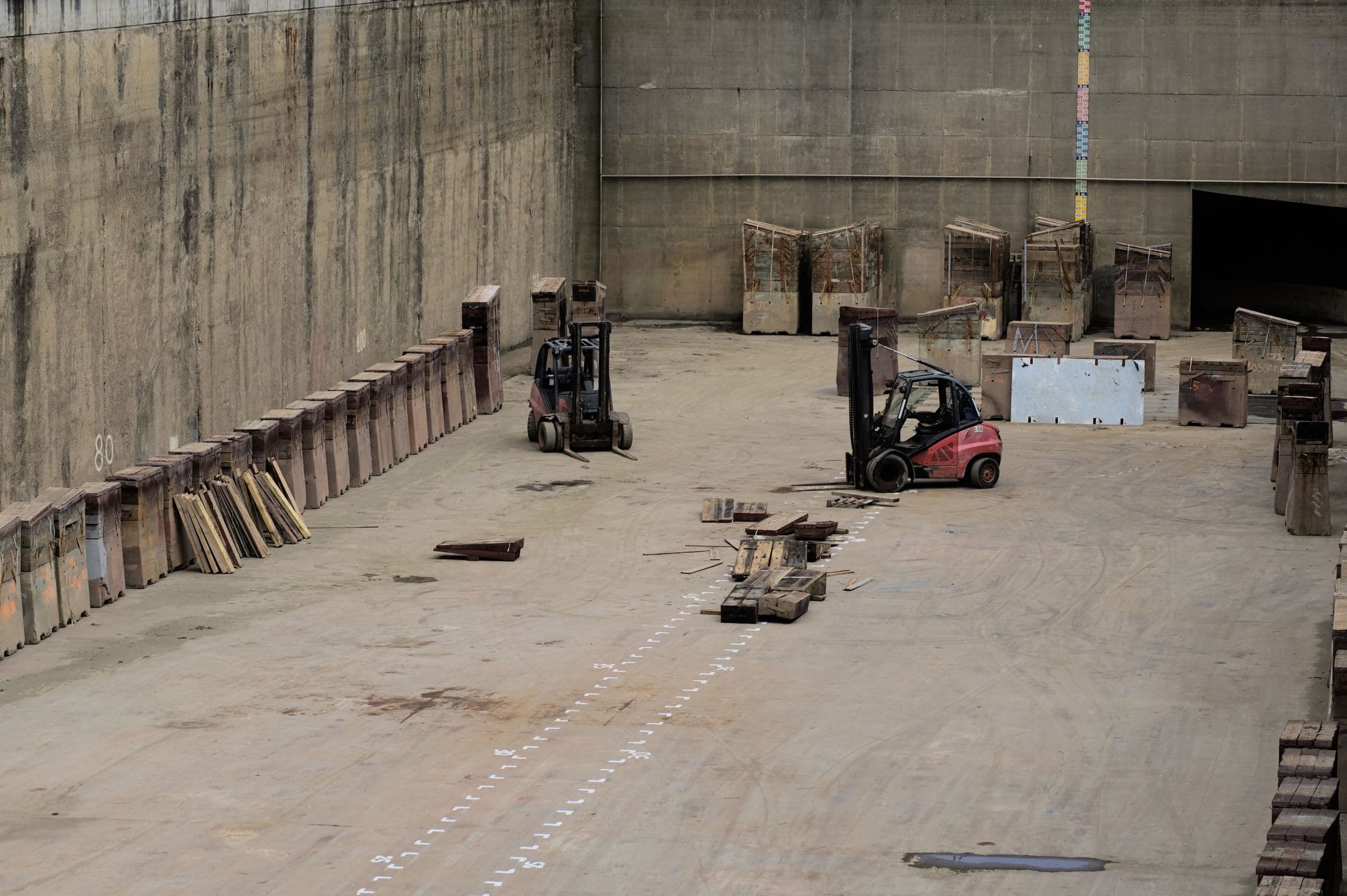 Forklifts moving stored machinery in a large industrial warehouse, representative of the scale and mechanical handling large packaging is built for