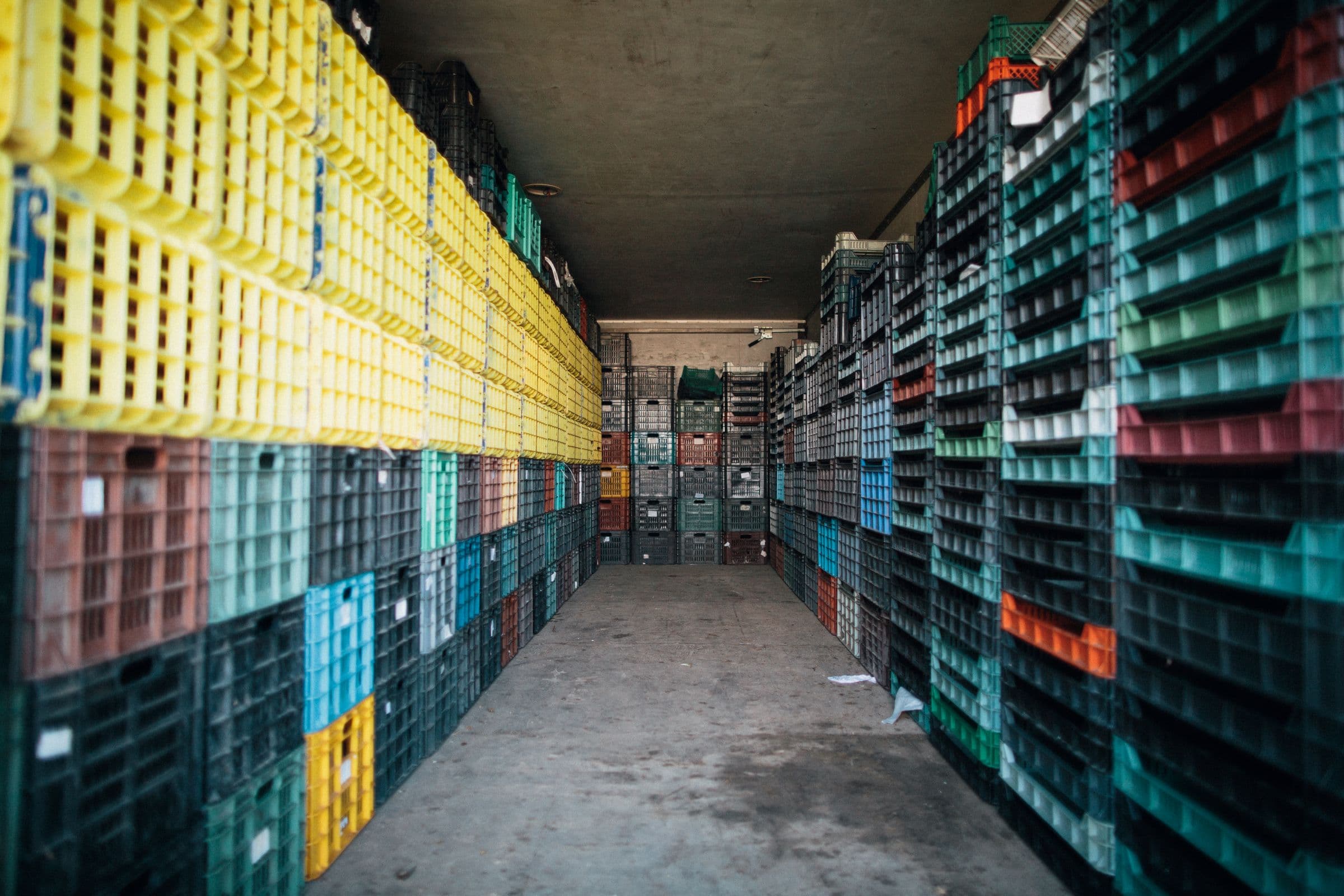 A wide industrial storage warehouse with rows of packaging on pallets, representative of the environment where IBCs and FIBCs are handled and stored