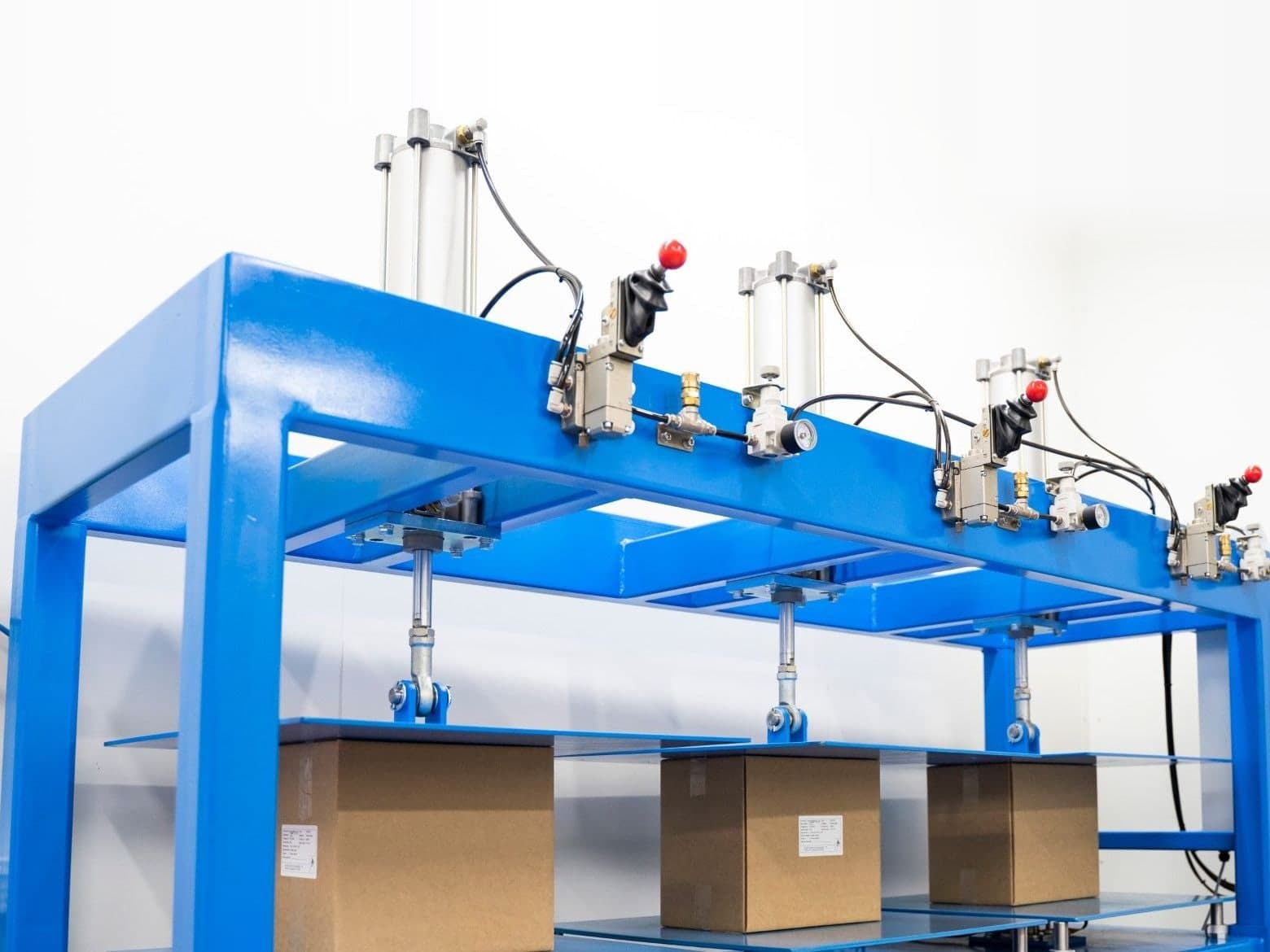 Falcon's blue pneumatic compression tester with three stations, each loading a cardboard box between steel platens