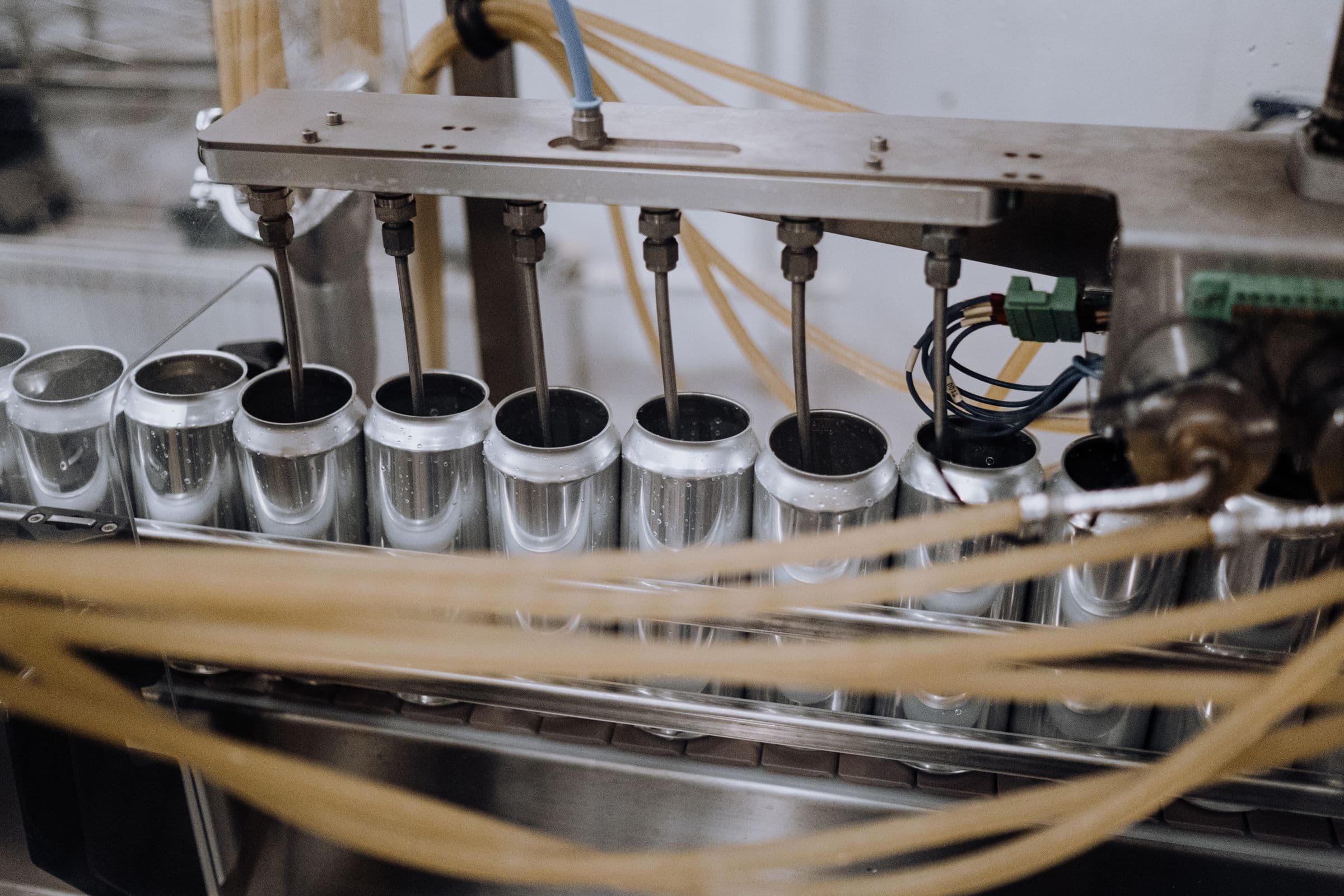 An automated metal can filling line in a modern factory — shown as a representative example of automated, repetitive can manufacturing, not a depiction of aerosol-specific production