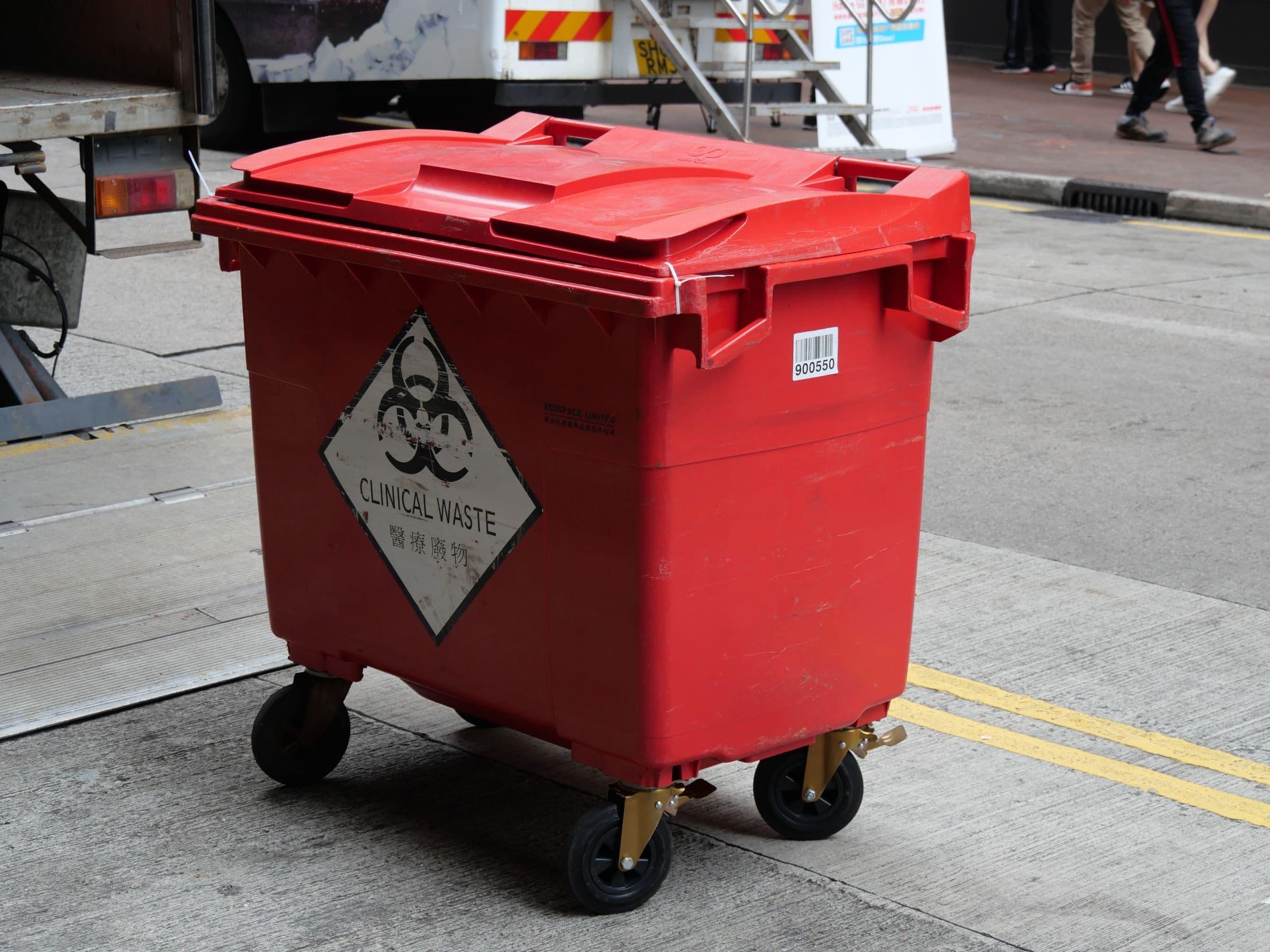 A red clinical/biohazard waste container marked for clinical waste, representative of the broader healthcare waste-management context sharps containers are used in