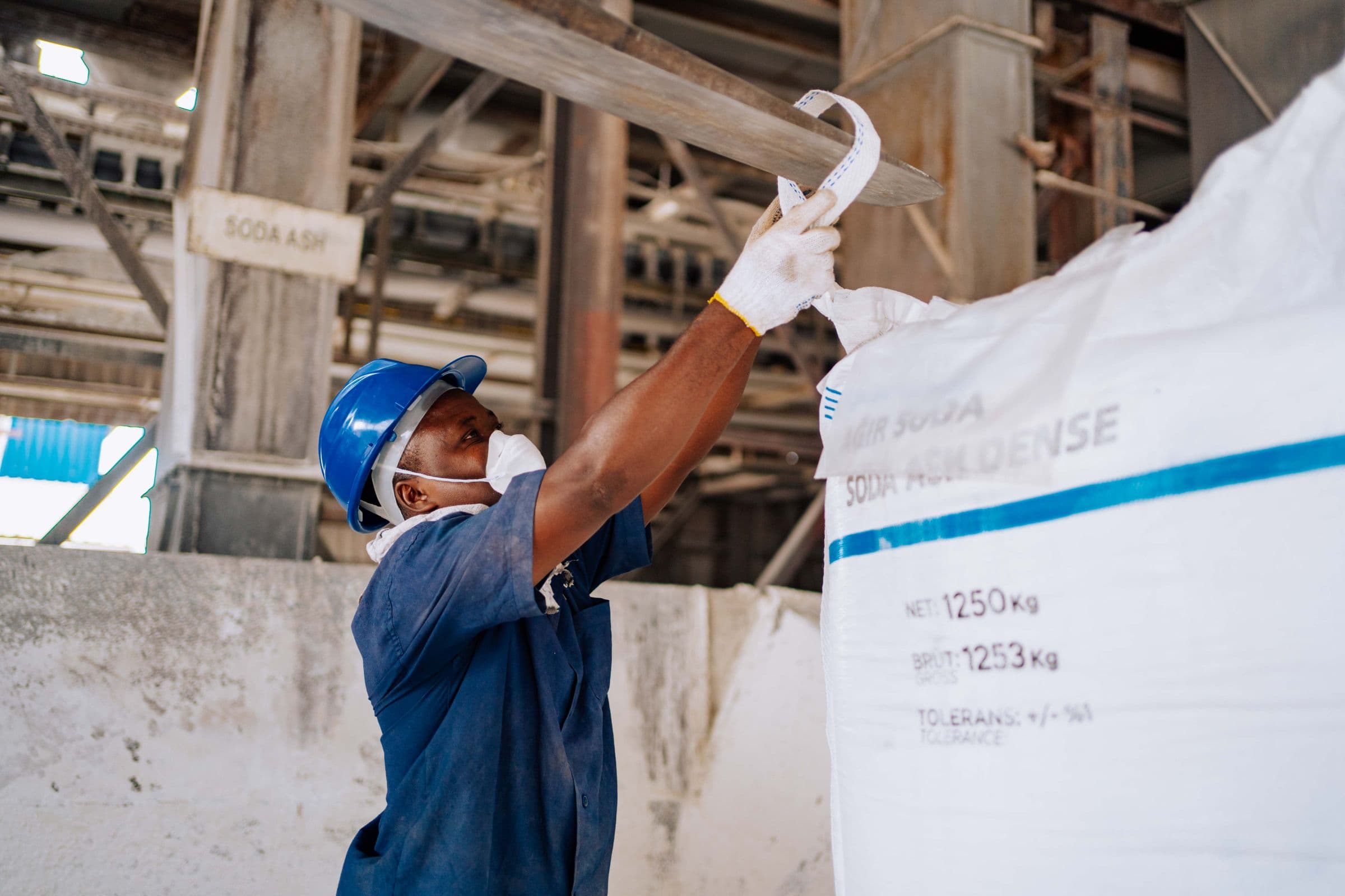 A worker lifting the loop of a woven flexible intermediate bulk container (FIBC) bag in a manufacturing facility