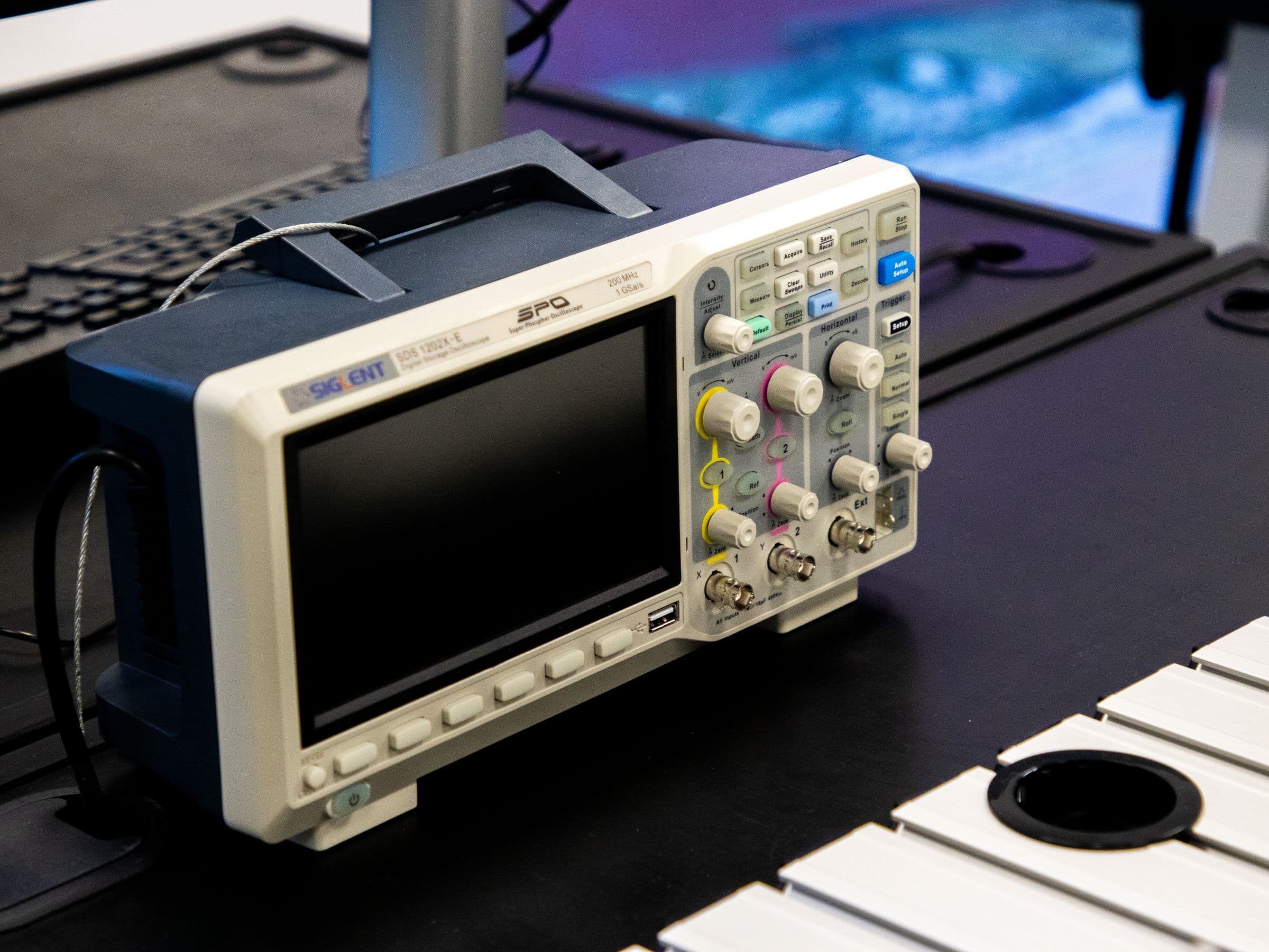 A digital oscilloscope and instrumentation on a laboratory workbench, representative of the measurement equipment used in custom test programs