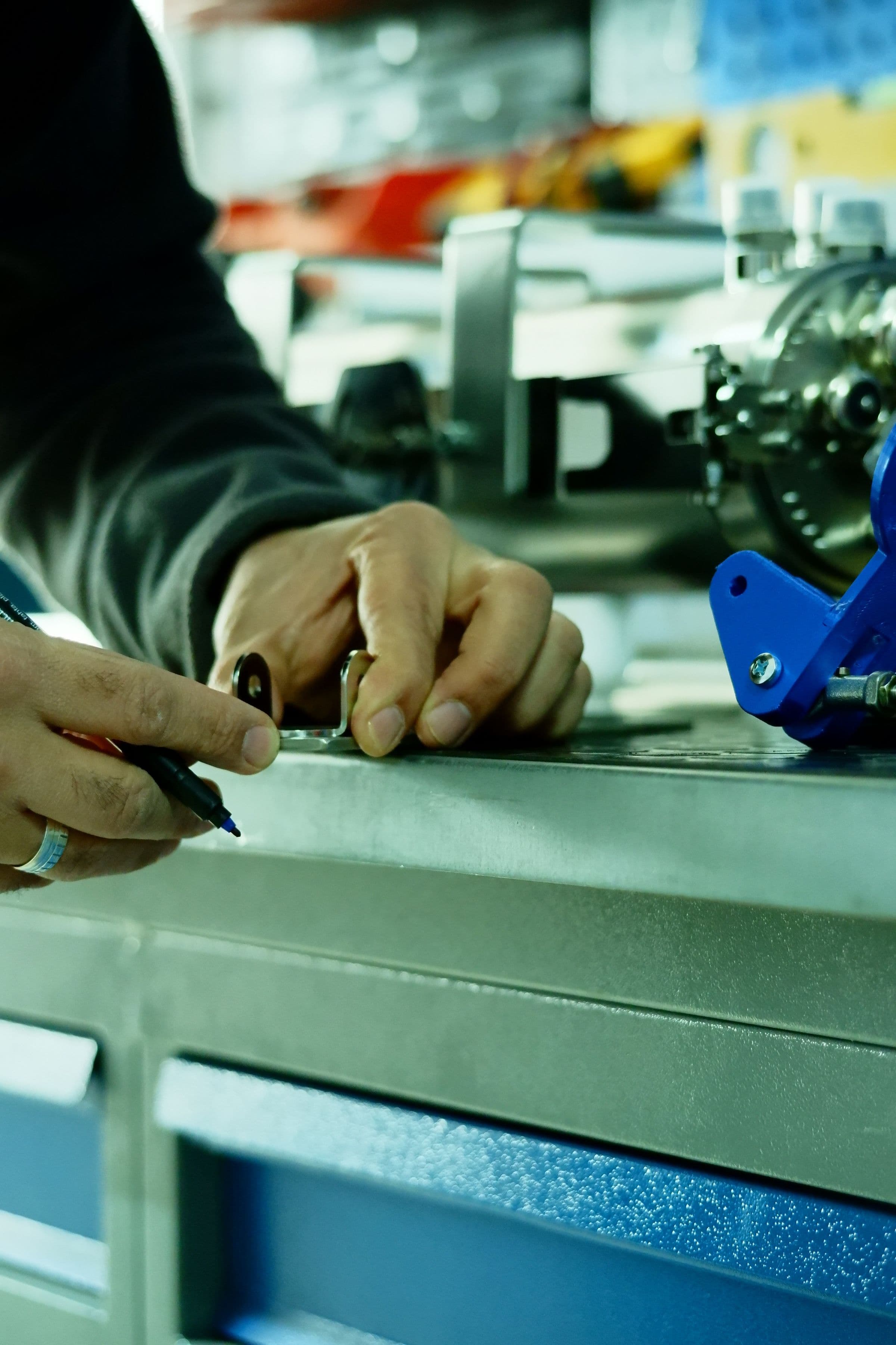 Hands using precision measurement tools on an engineered metal component in a mechanical workshop
